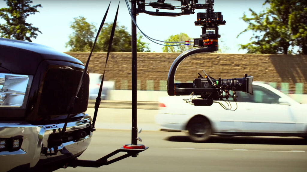 An image of a camera rig on the front of a car as it drives along filming another car